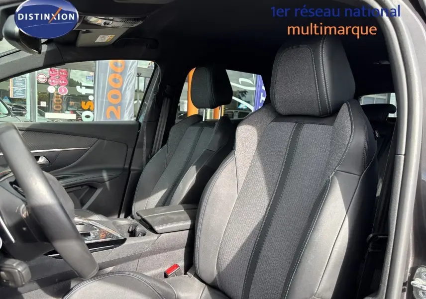 Vue intérieure côté conducteur du Peugeot 3008 HYBRID 180CH 2024, sièges tissu et cuir noir avec surpiqûres contrastées.