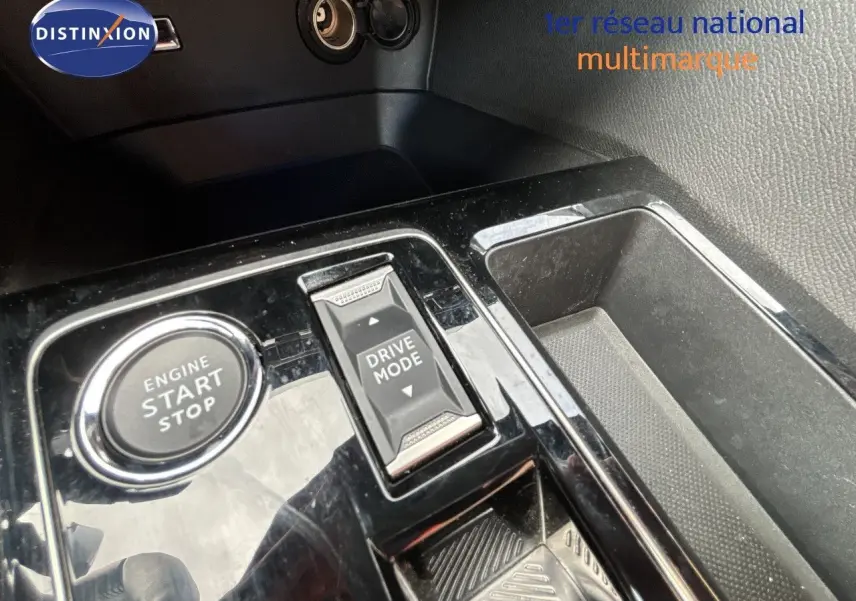 Gros plan sur la console centrale noire brillante du Peugeot 3008 Hybrid 2024 avec bouton start/stop et sélecteur drive mode.