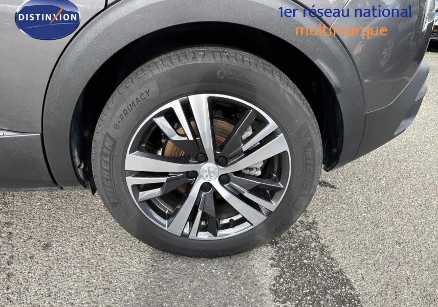 Gros plan sur la roue avant gauche du Peugeot 3008 gris platinium métal, avec jante alliage bicolore et pneu Michelin.