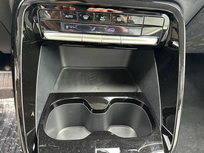 Vue rapprochée de la console centrale noire brillante du Citroën C3 Aircross 2026 avec commandes climatisation et porte-gobelets.