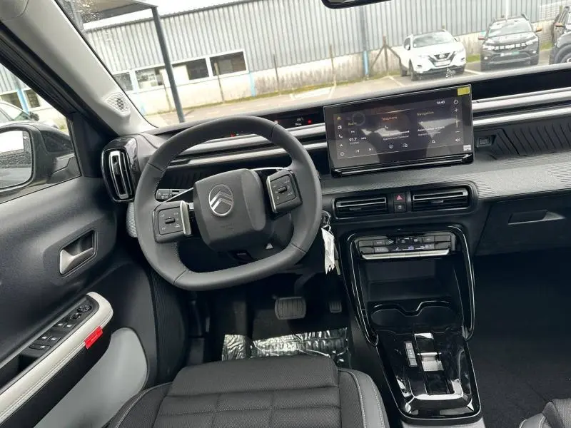 Vue intérieure avant gauche du Citroën C3 Aircross 2026, tableau de bord noir avec écran tactile et volant multifonction.