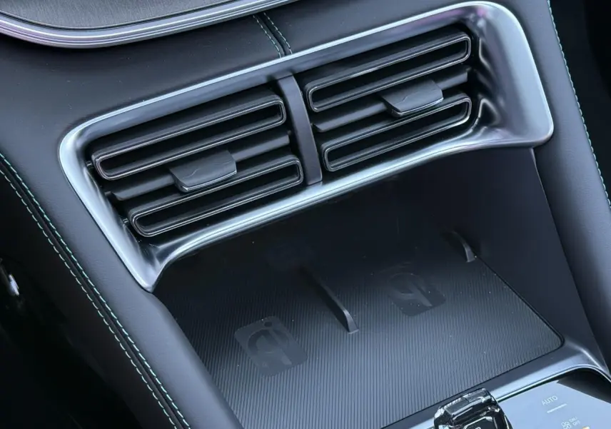 Gros plan sur la console centrale intérieure noire du BYD SEAL U 1.5 DM-i 218 Boost avec prises de ventilation et zone de charge sans fil.