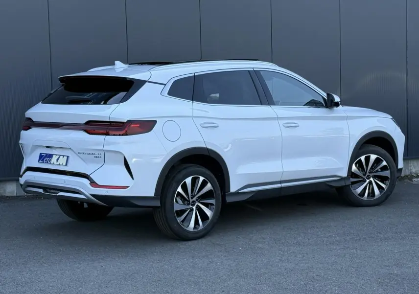 Vue 3/4 arrière droite du SUV BYD SEAL U 1.5 DM-i 218 Boost en blanc Snow White avec jantes bicolores et toit panoramique.