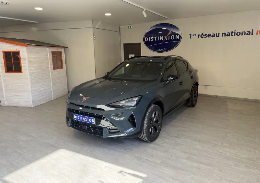 Vue 3/4 avant droite d'un CUPRA Formentor gris 2026 avec jantes noires, présenté en intérieur showroom.