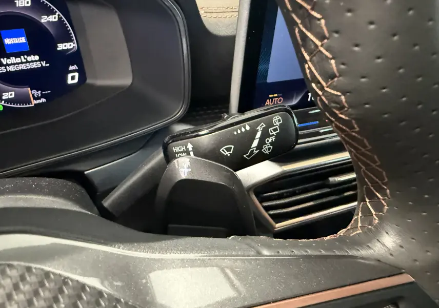 Gros plan intérieur sur le commodo de lève-glace et volant perforé avec surpiqûres marron du Cupra Formentor gris 2026.