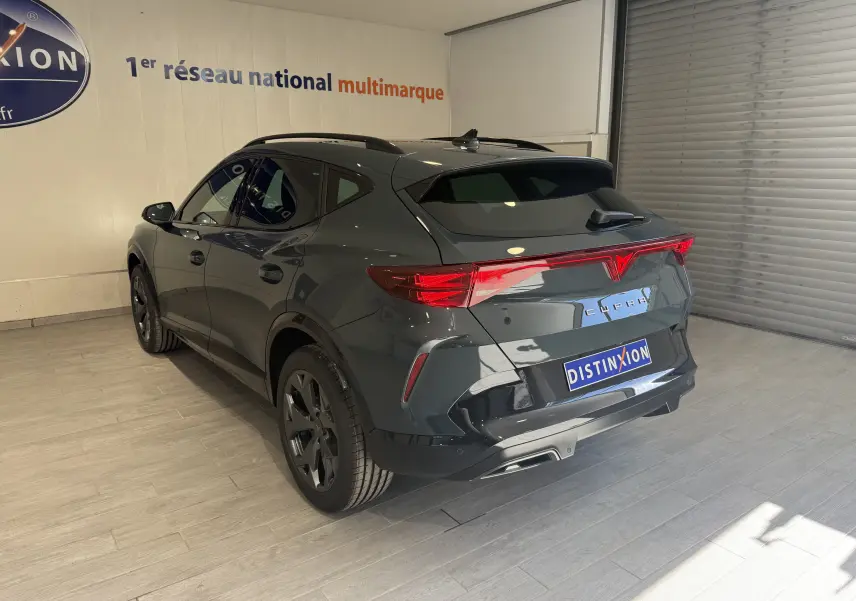 Vue 3/4 arrière droite d’une CUPRA Formentor gris métallisé 2026 avec feux arrière LED et jantes noires en showroom.