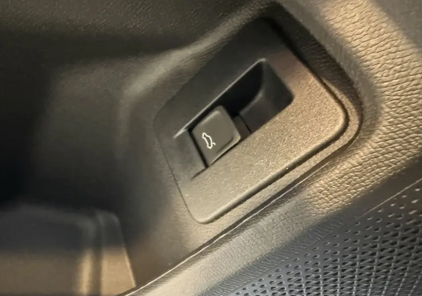 Gros plan sur le bouton d'ouverture du coffre intérieur en plastique noir du CUPRA Formentor gris 2026.