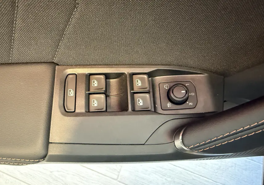 Gros plan sur les commandes de lève-vitres et réglage des rétroviseurs côté conducteur du CUPRA Formentor gris.