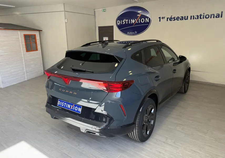 Vue 3/4 arrière droite d'un CUPRA Formentor gris 2026 avec feux arrière LED et jantes noires en intérieur showroom.