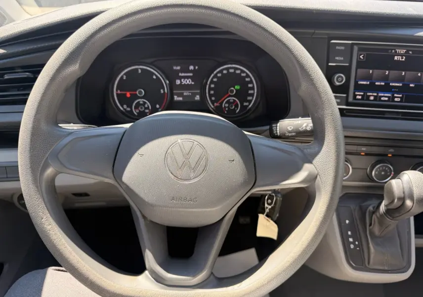 Vue intérieure centrée sur le volant Volkswagen du Transporter 2023 avec tableau de bord et écran tactile visibles.