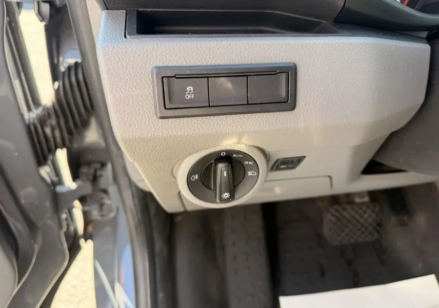 Vue rapprochée du tableau de bord côté gauche du Volkswagen Transporter gris clair, avec commande des phares et bouton antipatinage.