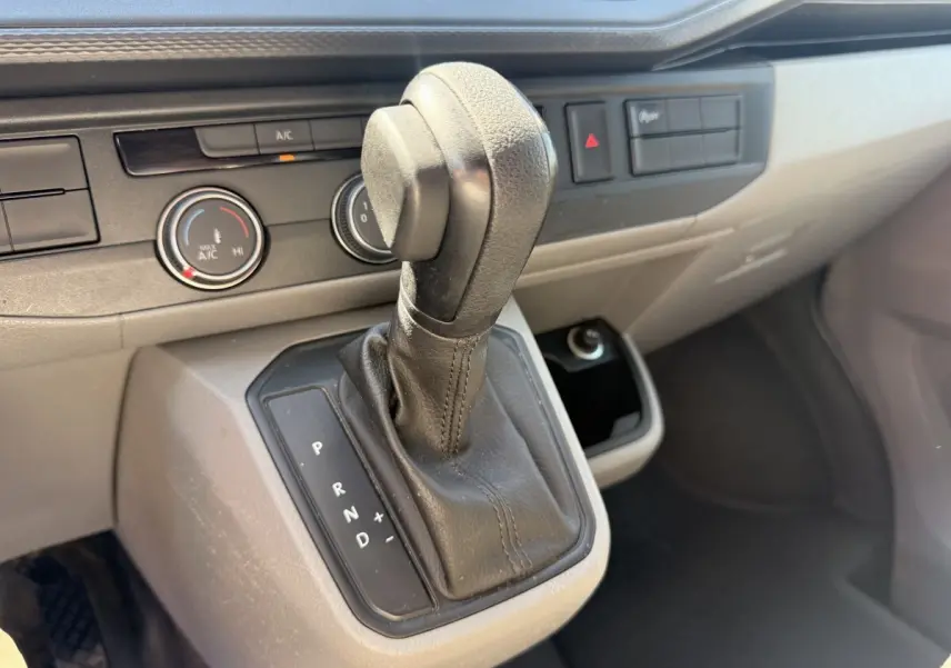 Gros plan sur la commande de boîte automatique noire dans l’habitacle gris clair du Volkswagen Transporter 2023.