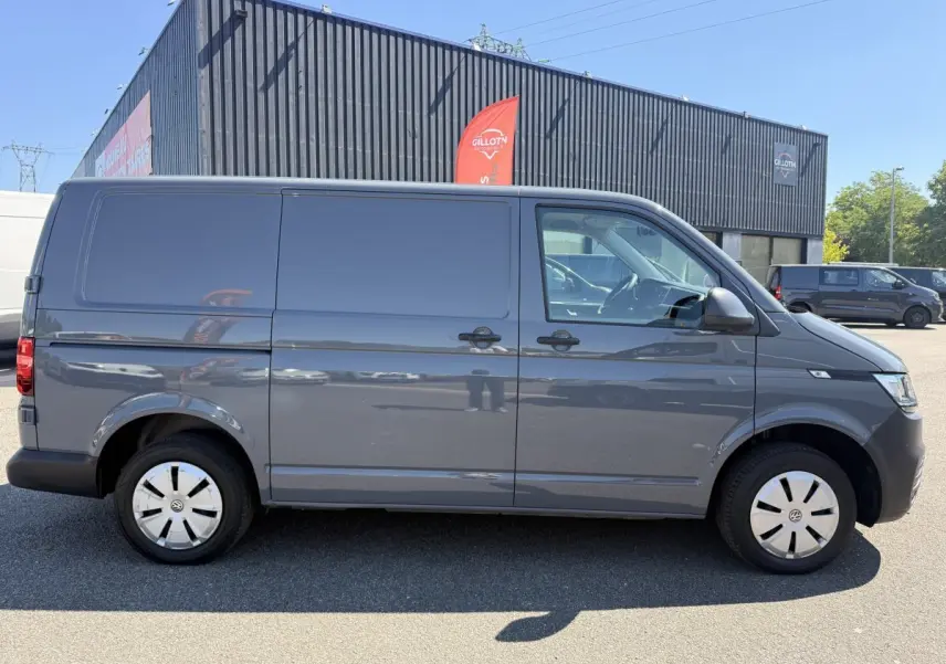Vue latérale droite d’un Volkswagen Transporter gris clair 2023, fourgon utilitaire avec jantes acier et vitres teintées.