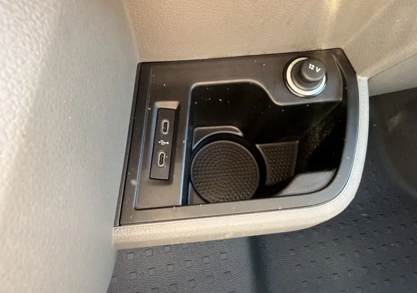 Gros plan sur la console centrale noire avec prises USB-C et prise 12V du Volkswagen Transporter gris clair 2023.