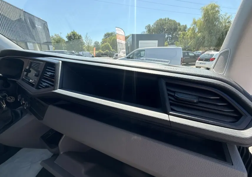 Tableau de bord gris du Volkswagen Transporter 2023 vu de l’intérieur côté passager avec écran tactile et aérateurs.