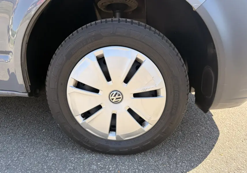 Gros plan sur la roue avant droite grise d’un Volkswagen Transporter 2023 avec enjoliveur blanc marqué VW.