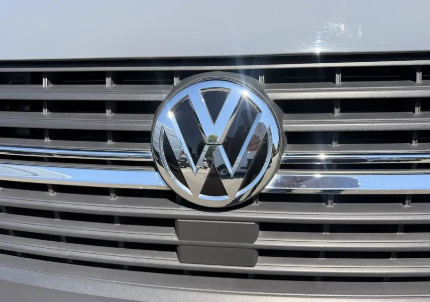 Gros plan sur la calandre grise claire du Volkswagen Transporter 2023 avec logo VW chromé brillant au centre.