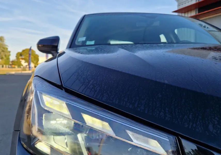 Gros plan sur le phare avant gauche d’un Audi Q2 noir 2021, mettant en valeur les LED et la carrosserie brillante.