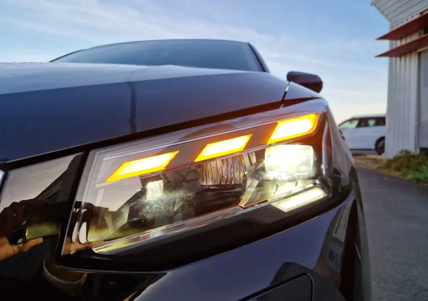 Gros plan sur le phare avant droit allumé d’un Audi Q2 noir, mettant en valeur ses feux LED distinctifs.
