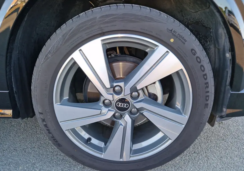 Gros plan sur la roue avant droite de l'Audi Q2 noire, mettant en valeur la jante alliage et le logo Audi central.