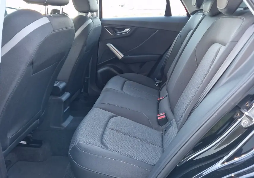 Vue intérieure côté droit des sièges arrière noirs de l'Audi Q2 35 TFSI 2021, avec habillage tissu et ceintures visibles.