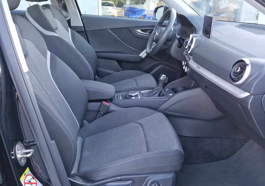 Intérieur noir de l'Audi Q2 35 TFSI 2021 vu côté conducteur, avec sièges sport et tableau de bord moderne.