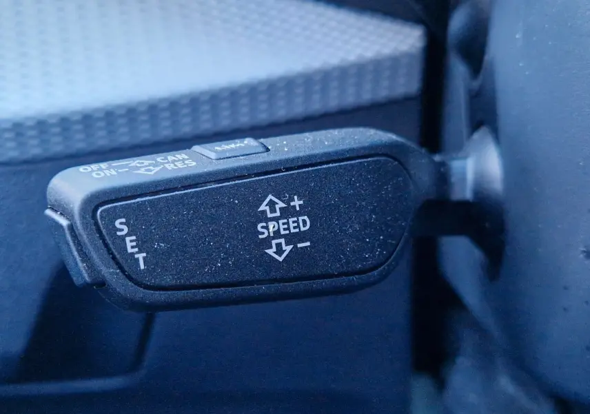 Gros plan sur la commande de régulateur de vitesse du volant d’un Audi Q2 noir, version S line 2021.