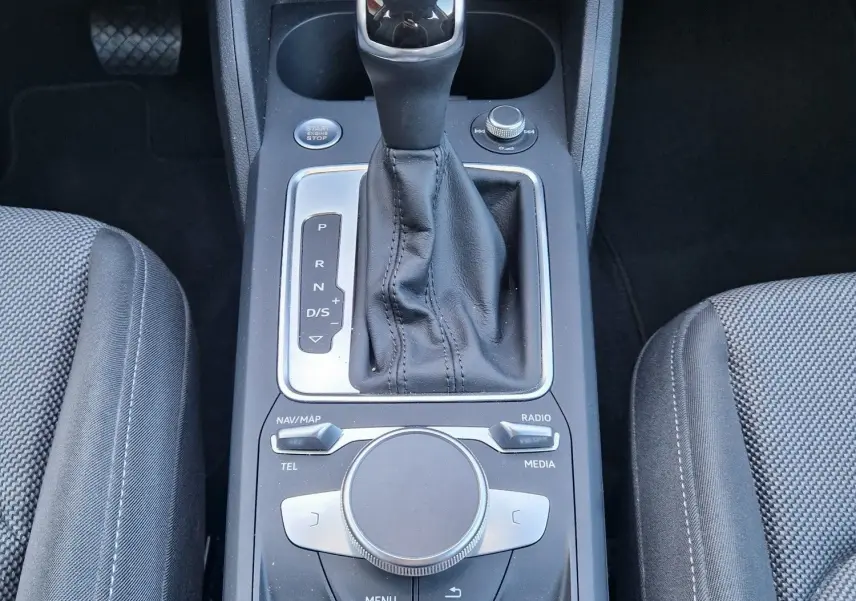 Vue plongeante sur la console centrale noire de l’Audi Q2 35 TFSI 2021, avec levier de vitesse automatique et commandes multimédia.