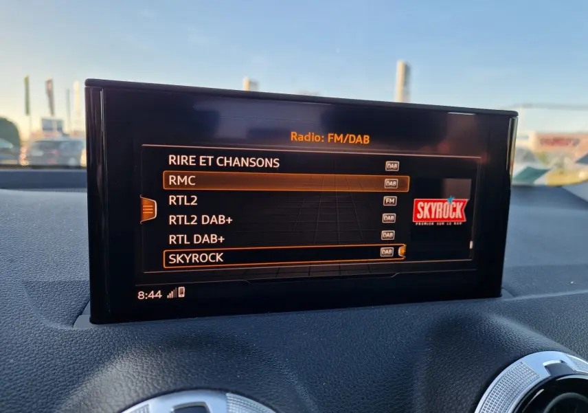 Écran central de l’Audi Q2 35 TFSI 2021 affichant les stations radio FM/DAB avec sélection sur Skyrock, intérieur noir.