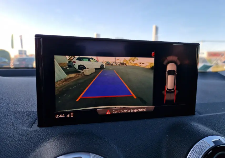 Écran intérieur de l'Audi Q2 35 TFSI 2021 montrant la caméra de recul avec trajectoire en bleu et vue 360° du véhicule.