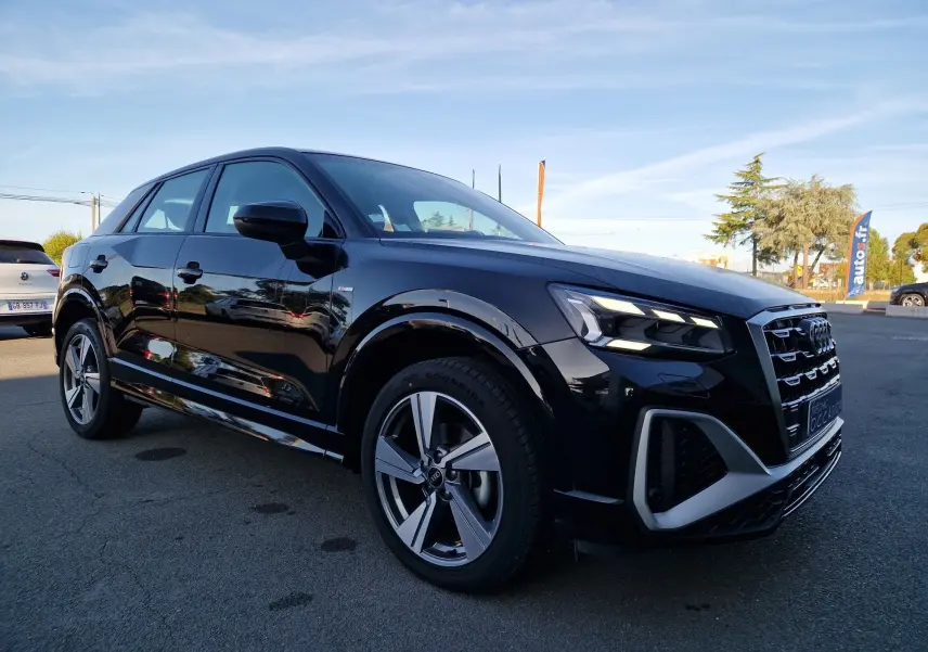 Audi Q2 noir en vue 3/4 avant droit, avec phares LED allumés et jantes alliage distinctives.