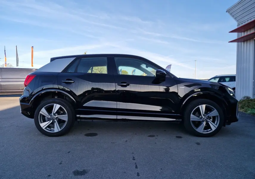 Audi Q2 noir vue de profil côté gauche, finition S line avec jantes alliage et toit contrasté gris.