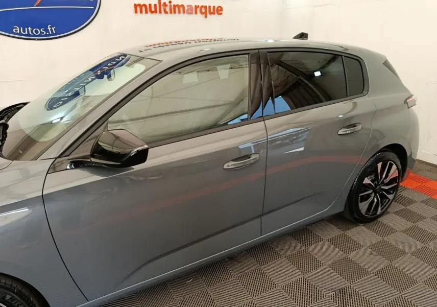 Profil côté gauche d’une Peugeot 308 gris foncé 2026 avec jantes alliage et rétroviseur noir brillant.