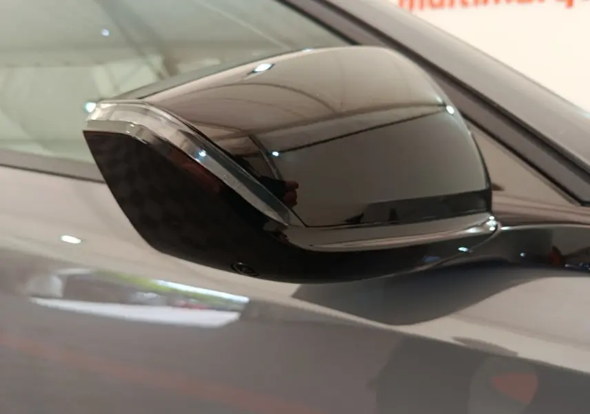 Gros plan sur le rétroviseur droit noir brillant d'une Peugeot 308 gris foncé, reflet de l'environnement intérieur visible.