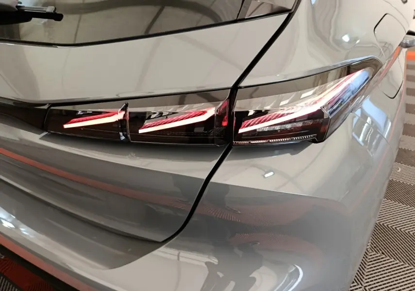 Gros plan sur le feu arrière droit LED d'une Peugeot 308 gris foncé, version 2026, avec lignes lumineuses distinctives.