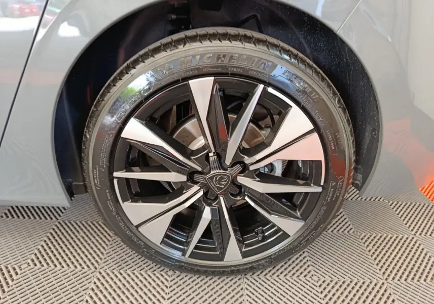Gros plan sur la roue avant droite d’une Peugeot 308 gris foncé, avec jante alliage noire et argentée au design moderne.