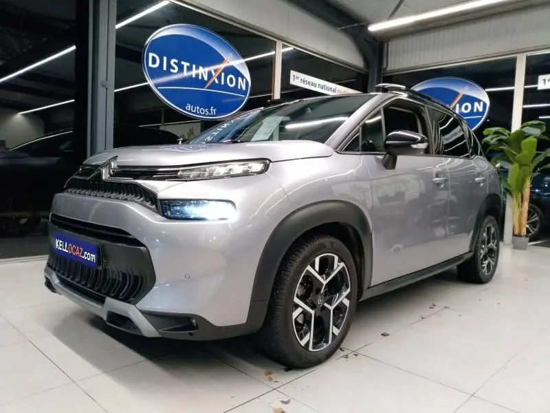 Citroën C3 Aircross gris en 3/4 avant droit, avec ses phares allumés et jantes distinctives en concession.