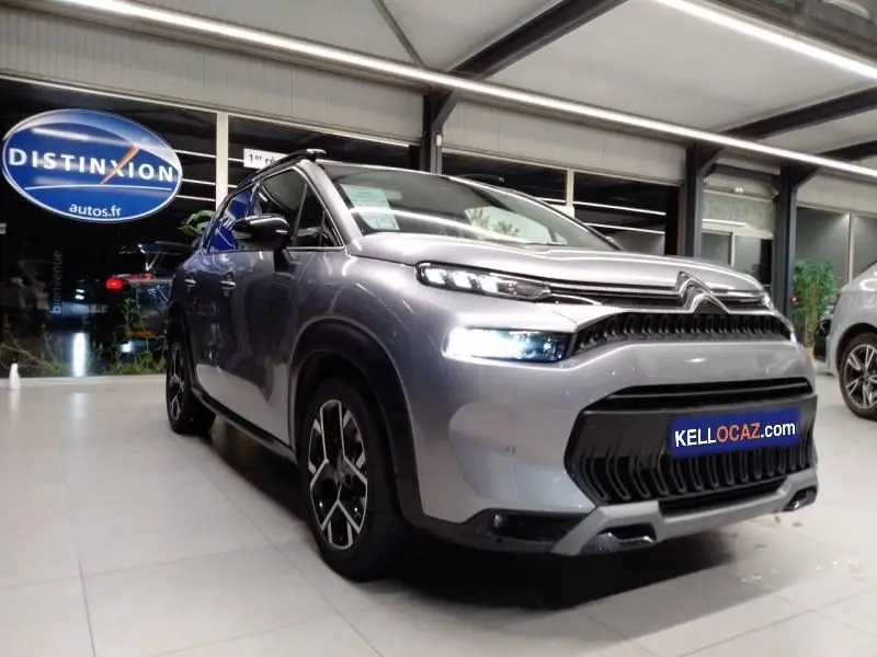 Citroën C3 Aircross gris 3/4 avant droit en showroom, avec feux LED allumés et jantes alliage distinctives.