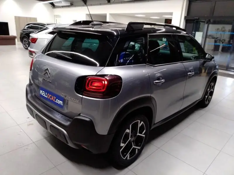 Vue 3/4 arrière droite d'un Citroën C3 Aircross gris 2022 avec toit noir et feux arrière LED distinctifs.