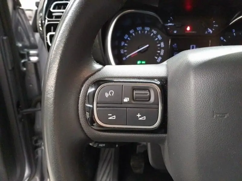 Gros plan sur les commandes au volant à gauche du Citroën C3 Aircross gris 2022, avec tableau de bord en arrière-plan.