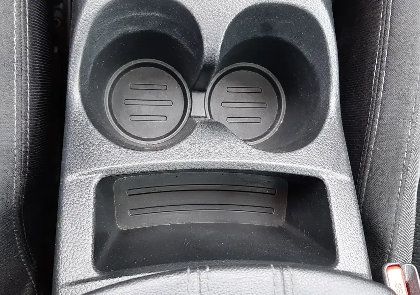 Vue plongeante sur le porte-gobelets noir et la console centrale en tissu gris foncé du Nissan Qashqai DCI 115 N-Connecta 2020.