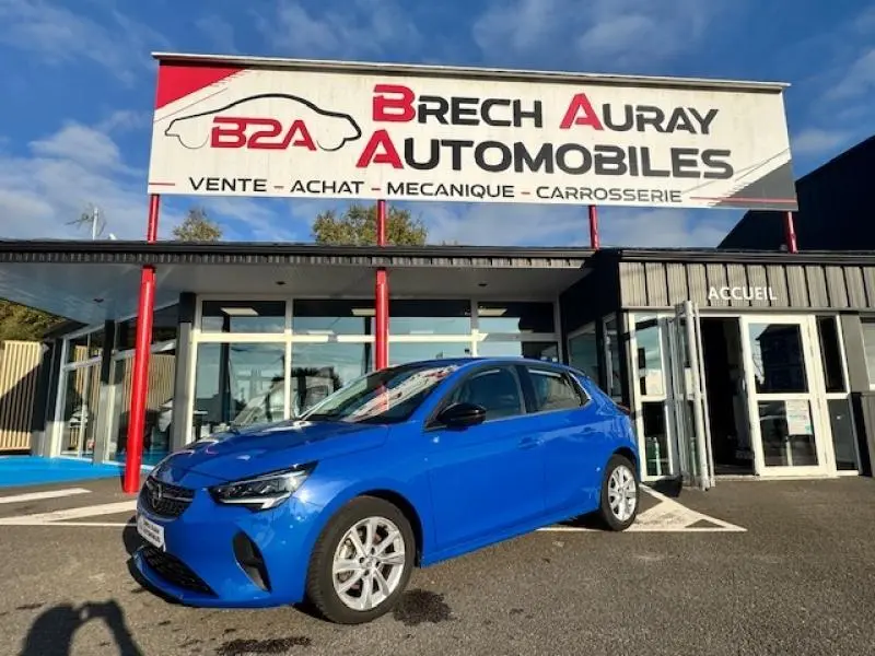Opel Corsa 1.2 Turbo Elegance bleu voltaïque en 3/4 avant droit devant un garage Brech Auray Automobiles.