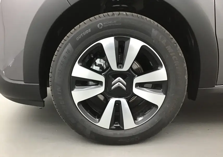Gros plan sur la roue avant gauche d'une Citroën C3 2022 gris platinium avec jante alliage bicolore et logo Citroën.