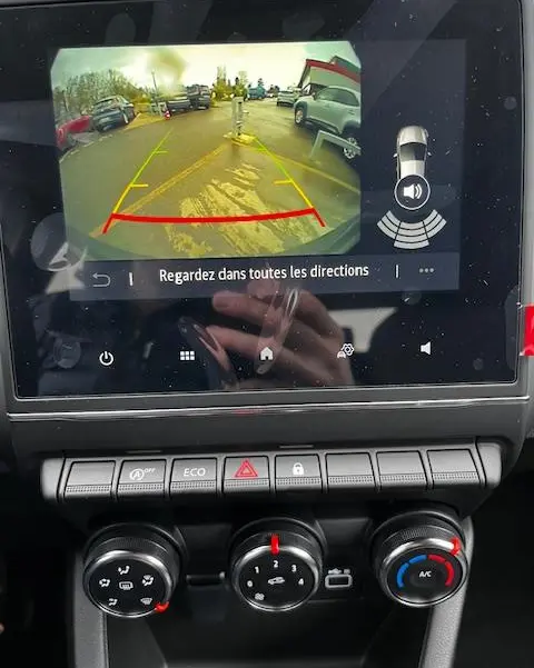 Écran tactile central montrant la caméra de recul d’une Renault Clio noire avec commandes climatisation en dessous.