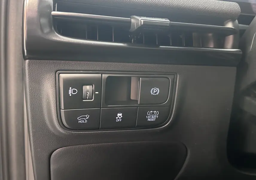 Gros plan sur les boutons de commande intérieurs du Hyundai Tucson gris Ecotronic, incluant frein à main électronique et contrôle de stabilité.