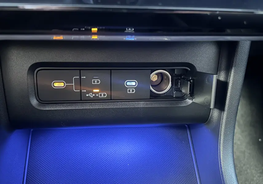 Gros plan sur la console centrale du Hyundai Tucson 2025, montrant les ports USB et prise 12V avec éclairage bleu.
