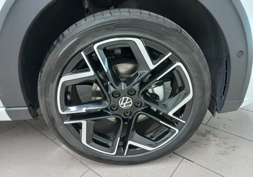 Gros plan sur la roue avant droite du Volkswagen Taigo blanc pur 2025 avec jante alliage noir et argent R-Line.