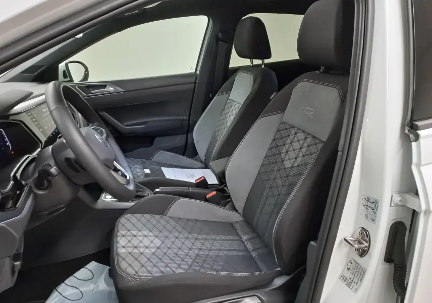 Vue intérieure côté conducteur du Volkswagen Taigo blanc pur 2025, sièges sport R-LINE avec motifs géométriques distinctifs.
