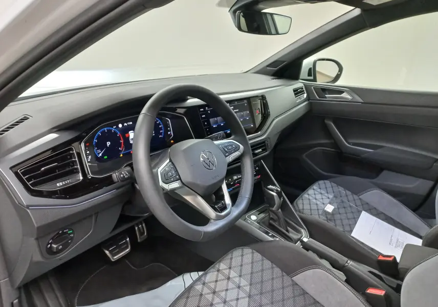 Vue intérieure côté conducteur du Volkswagen Taigo 2025 avec volant multifonction, tableau de bord digital et sièges tissu à motifs.