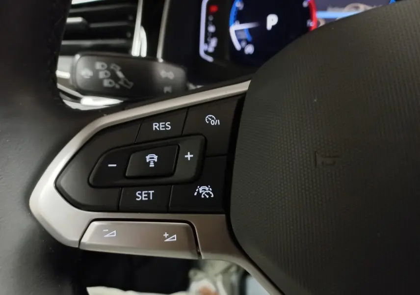 Gros plan sur les commandes au volant côté gauche du Volkswagen Taigo 2025, finition R-Line avec régulateur adaptatif.
